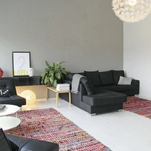 Elutoa krohvitud hall sein mõjub sobivalt «elavana», muutumata samas liiga domineerivaks. Valget laminaatpõrandat ilmestavad värvikad Rento Designi kaltsuvaibad, mis on tehtud taaskasutatud siidist. Põhulille meenutav rippvalgusti on Ikeast.