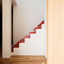 Korruseid ühendab erkpunaste astmetega männipuidust trepp.