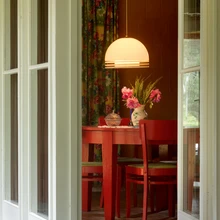 Õuest tuppa: punane söögilauamööbel ja Estoplasti tuntud rippvalgusti.