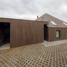 Tartus Emajõe ääres asuv eramu paistab silma kõrge ehituskvaliteediga; tumedast termosaarest fassaad ja selge arhitektuurne vorm haakuvad sümpaatselt jõeäärsete vanemate puitmajadega.